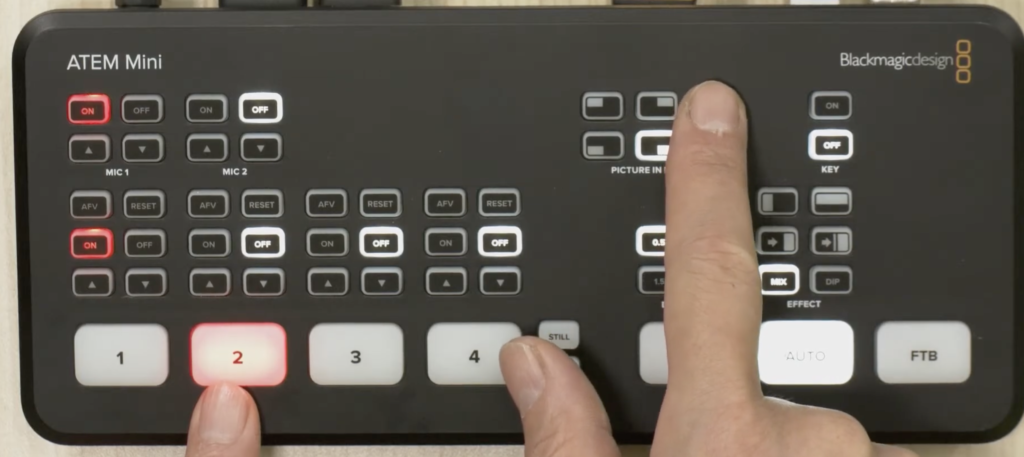 ATEM MiniのハードウェアパネルでHDMI Input 2ボタンとPICTURE IN PICTUREボタンを指で同時に操作している様子