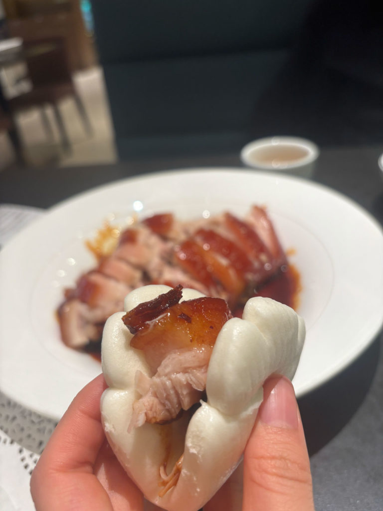 北京ダックの肉が白いお皿に盛り付けられている。背景に甘辛いソースが入った小皿と飲み物が見える