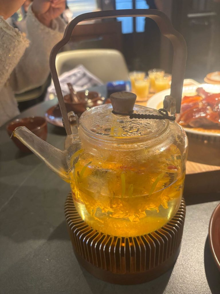 テーブルの上に置かれた中国茶の急須。背景に食べ物と飲み物が見える