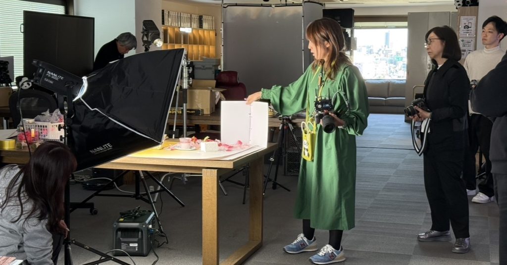写真家がスイーツのライティングをしている。それを生徒たちが見守る。