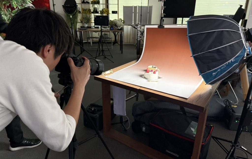 ケーキを本格セットで撮影する男性。