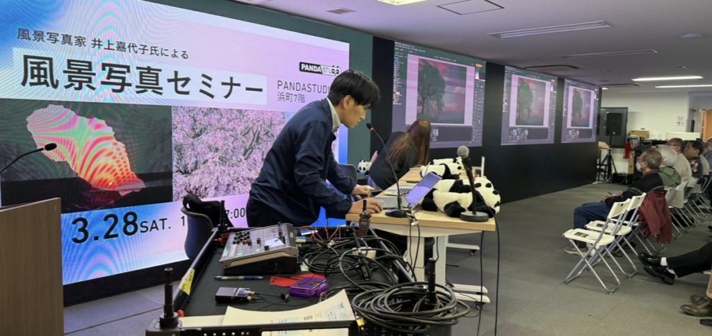 モニターを見ながら写真を調整していくところ。男性がPCを使って操作している。