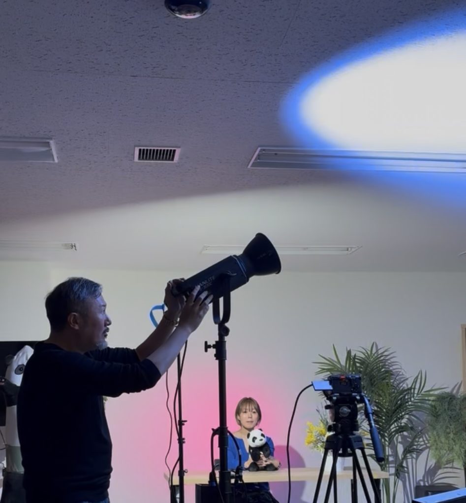 照明を天井に当てる映像作家
。モデル撮影の照明ライティング中。