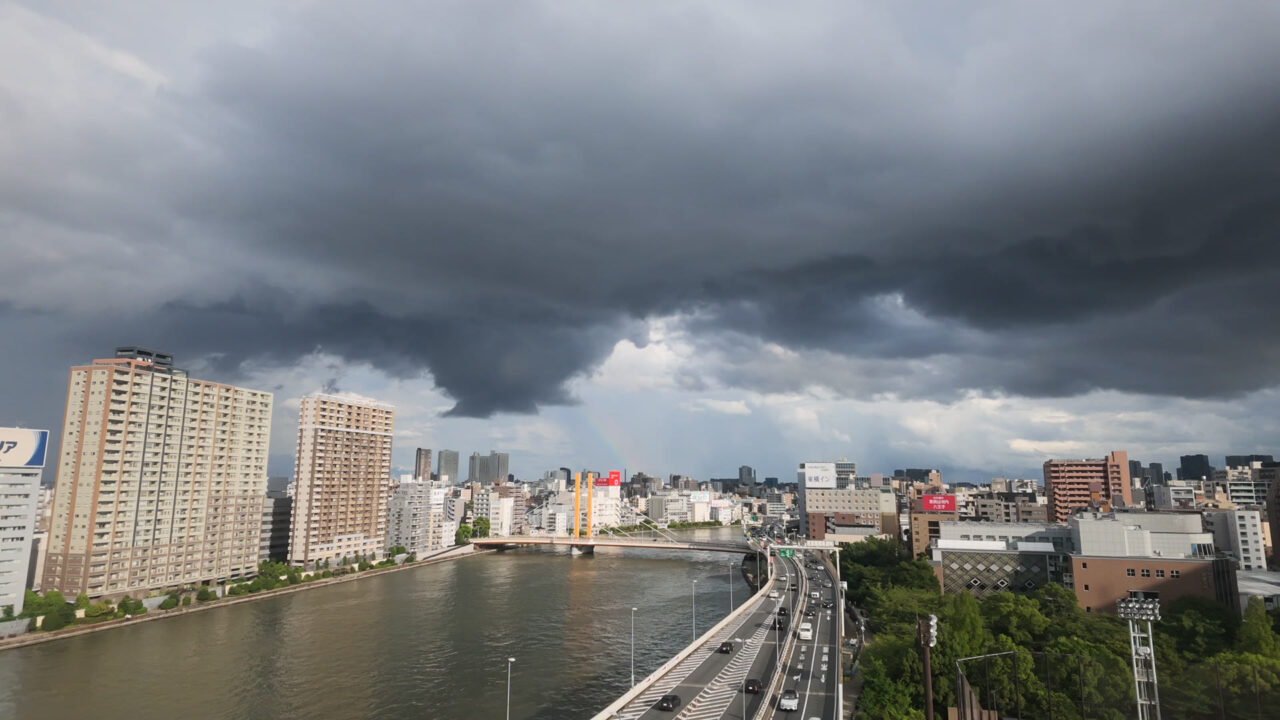 隅田川の上空に黒い雨雲が押し寄せてくる様子。ゲリラ豪雨の直前