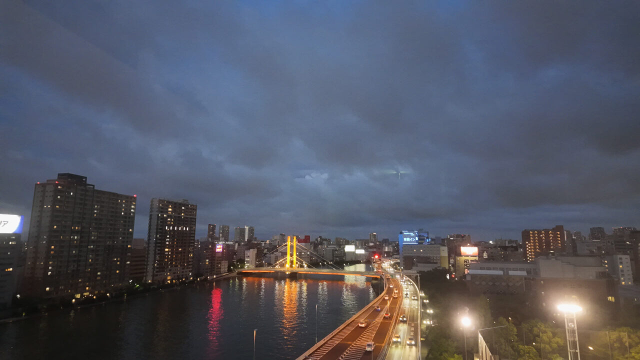 日没後の隅田川の夜景。ライトアップされた橋と首都高の車の光が水面に反射している