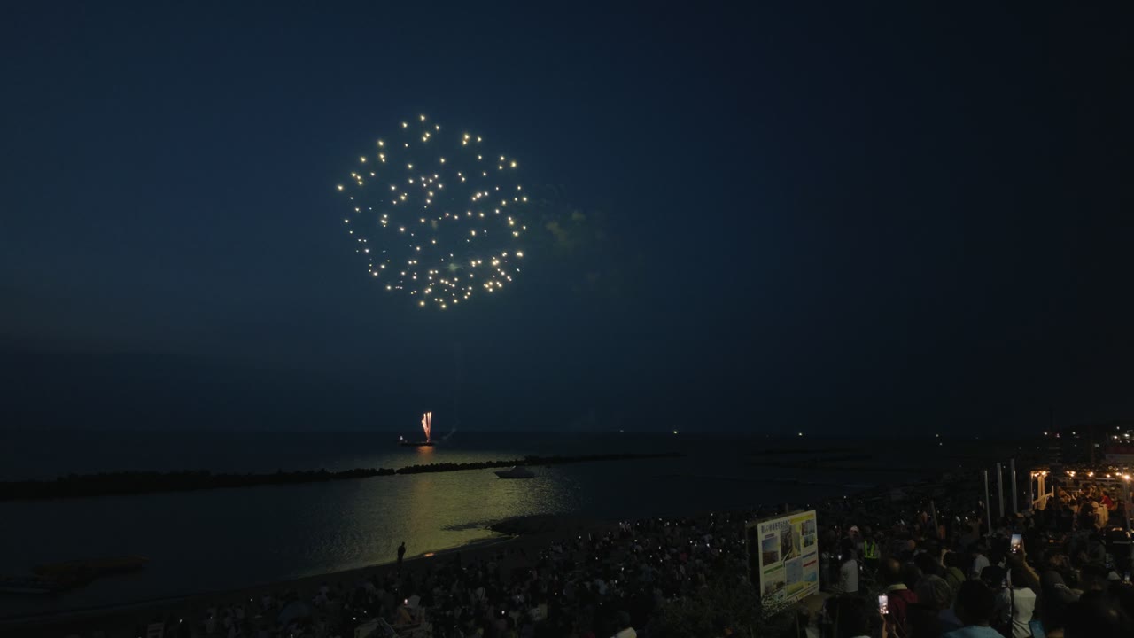 関屋浜の花火。手前に観客の頭、海面に花火の反射が入った引きの構図。Osmo Pocket 4P 広角 D-Log2 にLUT適用後