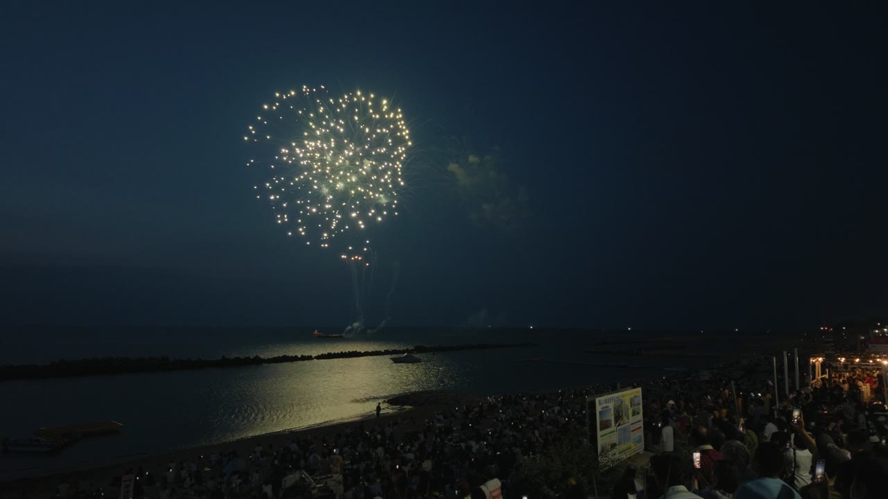 2倍スローにした一番明るい一発。金色の花火が開き、海面に反射している