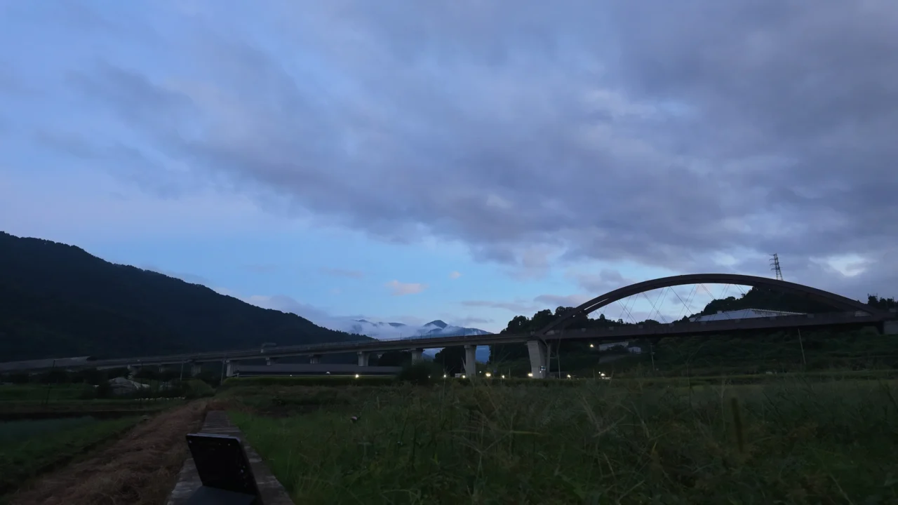 18時09分。薄明の青い空の下、リニア実験線のアーチ橋と高架。橋の街灯が点き始めている。通常タイムラプス2本目の冒頭